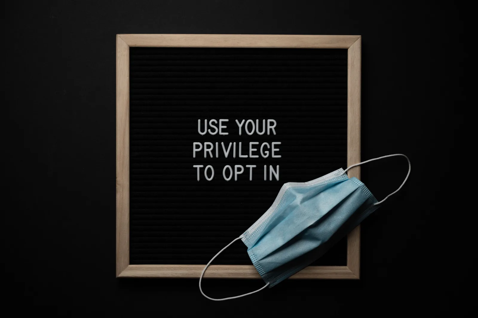 Top view of sterile mask on blackboard with Use Your Privilege To Opt In inscription on black background. Casl consent rules for social lead generation in Canada, explained