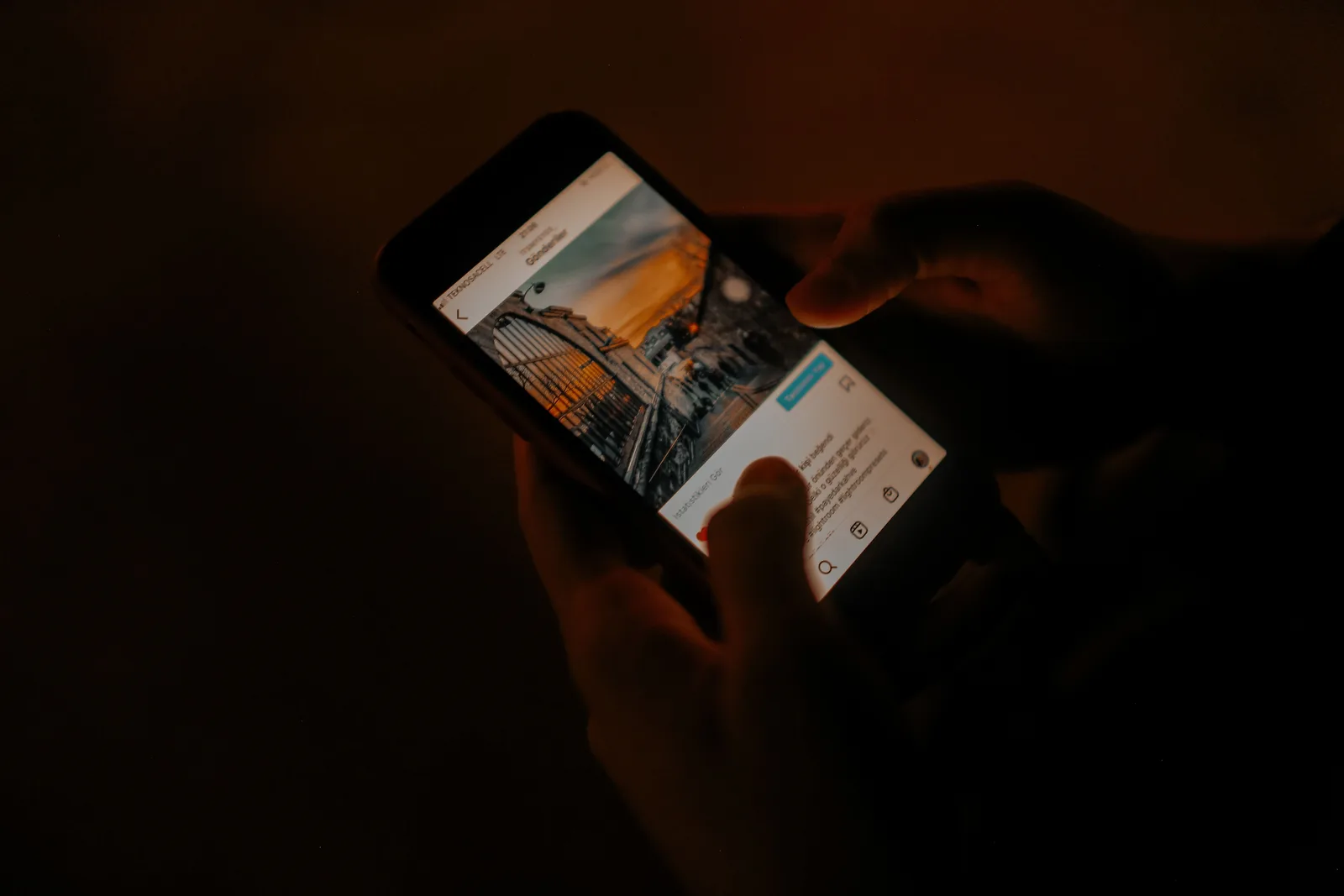 Hands holding a smartphone browsing social media in low light. What teams ask about organic social media growth