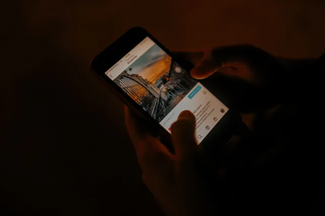 Hands holding a smartphone browsing social media in low light. What teams ask about organic social media growth