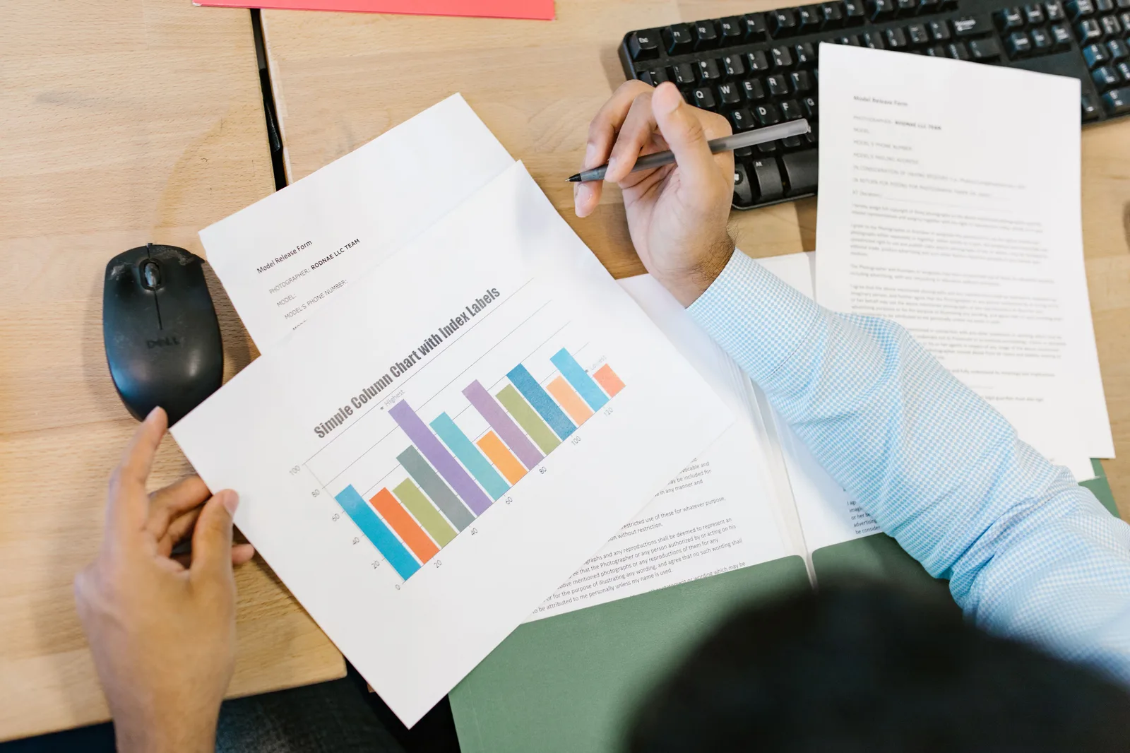 A business analyst reviews a colorful bar chart and documents at a desk, indicating data analysis. How to build influencer campaign management benchmarks