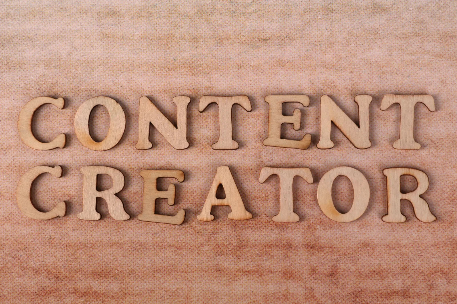 Wooden letters form 'Content Creator' on textured fabric background. Social media content planning: a practical guide