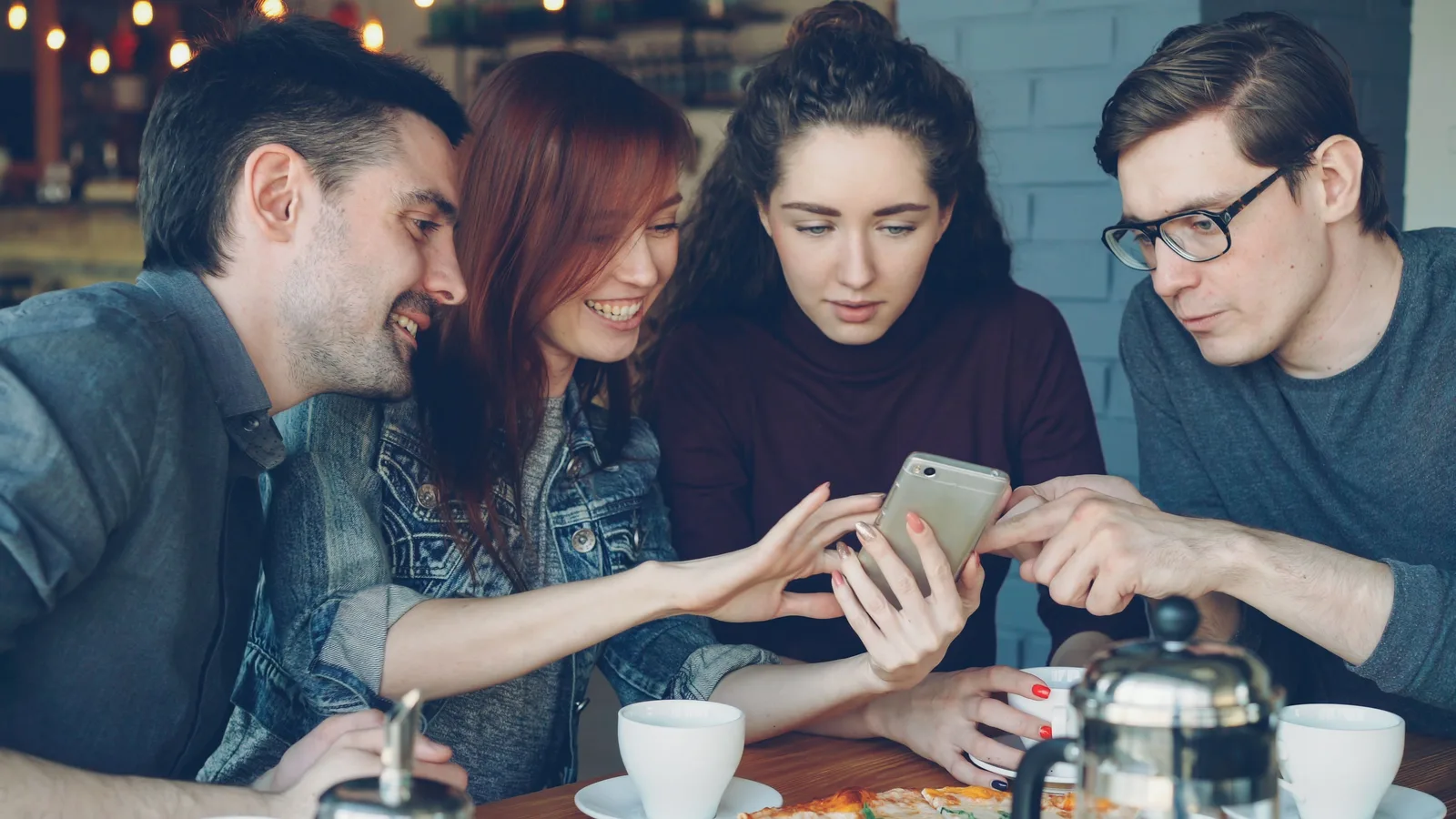 Group of friends sharing a moment with coffee and smartphones indoors. Social media strategy mistakes: using reach as a goal and seven more to fix